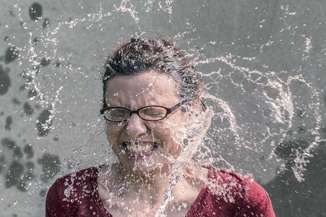 Egy multifokális szemüveglencsét viselő nő vizet fröccsen az arcára.