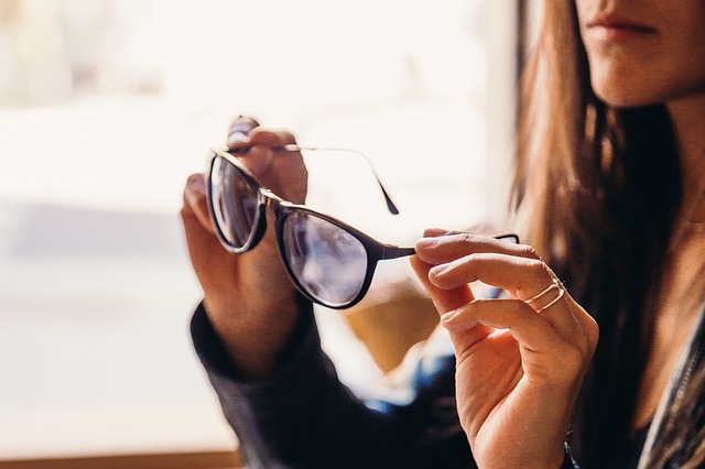 Egy nő a multifokális szemüvegét tartja a kezében az ablak előtt.