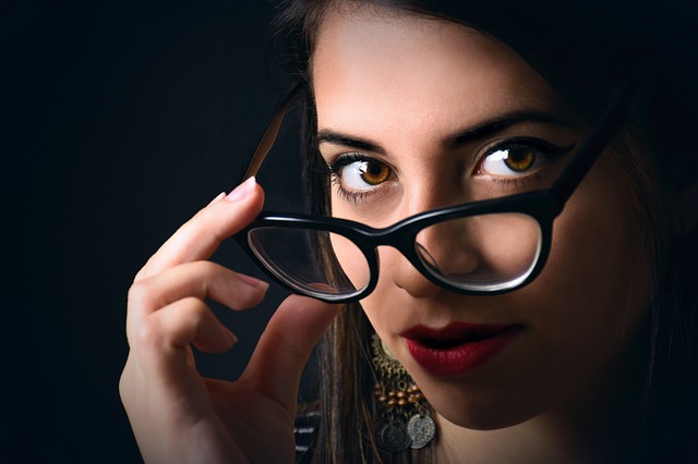 Egy nő multifokális lencsével ellátott szemüveget visel sötét háttér előtt. 