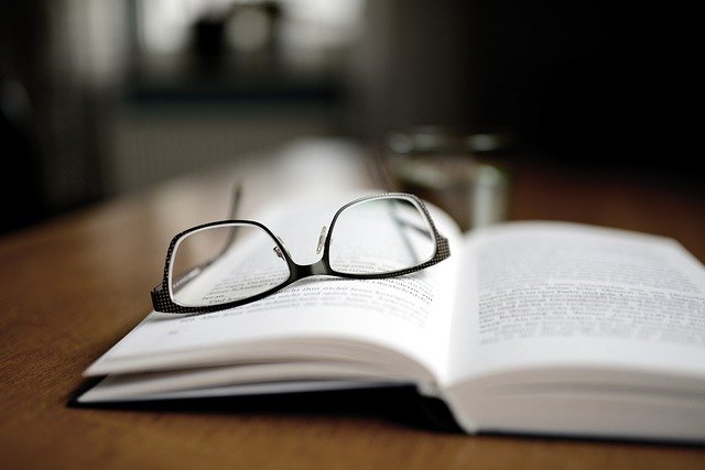 Egy asztalon fekvő könyv, rajta egy multifokális lencsével ellátott szemüveg.