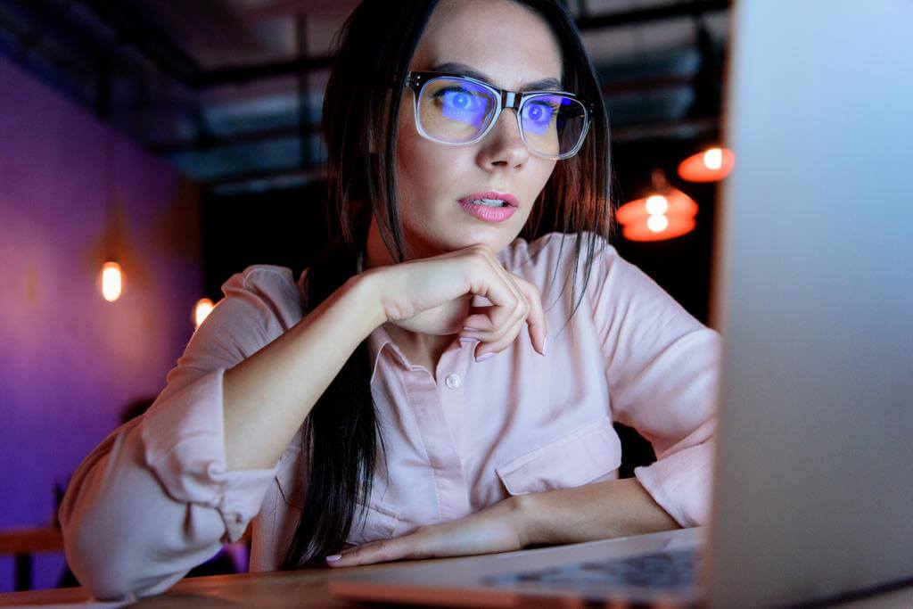 Fiatal nő laptopot bámul speciális bevonattal ellátott szemüvegben
