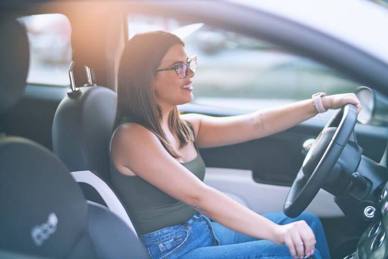 Fiatal nő szemüvegben autót vezet