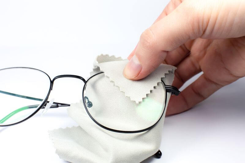 Női kéz törlőkendővel tisztítja a szemüveglencsét
